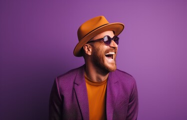 Vibrant portrait of a joyful man in a purple blazer and hat laughing heartily against a bold blue background. Ideal for expressing happiness, style, and individuality