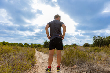 athlete on his back standing on a dirt road in the wilderness