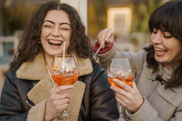 Women having a great time with spritz drinks - Two women radiate happiness as they enjoy their...
