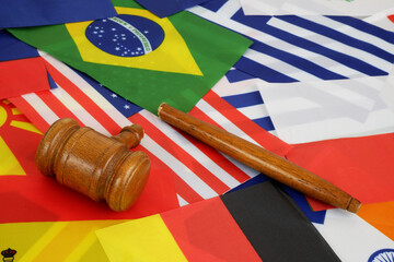 International laws and decisions problems concept. Broken wooden judge gavel on background of many national flags.