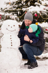 Portrait of happy father with cute kid boy with funny snowman in the park. Christmas and winter concept. - 669416584