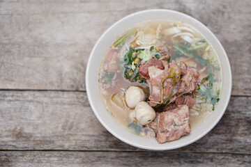 Stewed Pork Soup with meat balls and vegetables in bowl, old wooden background. Concept, traditional food. Favorite menu that can cook or order in noodle foodshops in Thailand.     