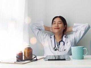 Telemedicine and healthcare concept. Asian female doctor relaxing at her workplace after done her work.
