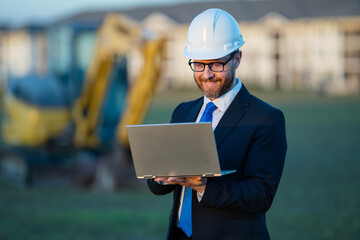 Architect at a construction site. Architect man in suit and helmet at construction site. Confident architect standing at construction. Investor or civil engineer. Outdoor portrait of hispanic