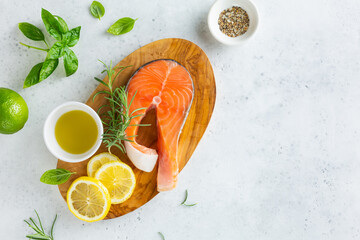 Top view of a fresh salmon steak with fresh rosemary, lemon and olive oil on a wooden board. Food background with space for text.