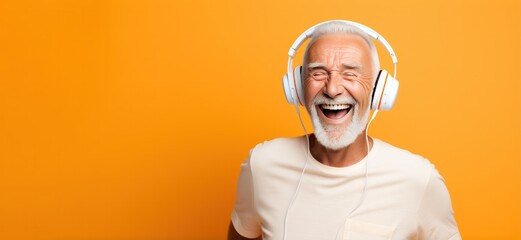 senior man laughing in headphones listening to music orange background banner