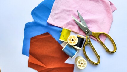 Amidst the pristine white backdrop, the scissors, needle, and thread are meticulously laid out,...