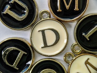 white and gold initial 'D' pendant in the middle of several letters