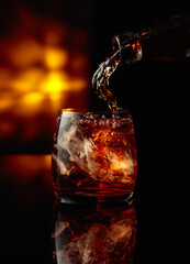 Pouring whiskey into a glass with ice.