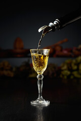 Yellow herbal liquor is poured from a vintage bottle into a glass.
