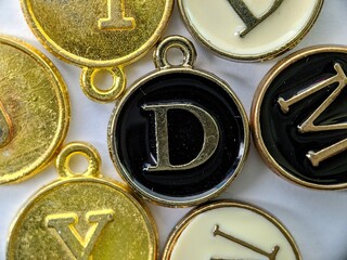 Black and gold initial 'D' pendant in the middle of several letters