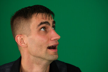 green background chromakey close-up dark hair young man. Scared man with stubble, screaming in...