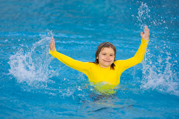 Excited child swimming. Little kid playing in blue water of swimming pool on a tropical resort at the sea. Cute boy swimming in pool water. Child splashing and having fun in swim pool.