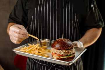 The chef is holding a thick juicy burger in his hands. A close-up view - Powered by Adobe