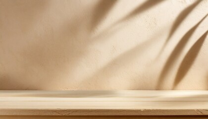 Empty table against beige textured wall background. Composition with monstera leaves shadows on the...
