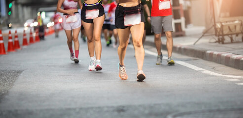 Selective focus to road surface with blurry human foot marathon race on city streets.