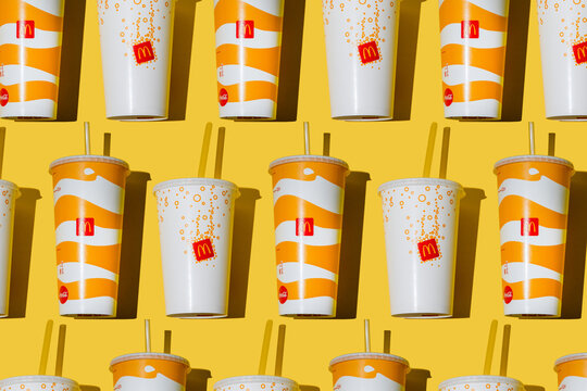 Yellow glass of McDonald's. Paper cup with lid. Takeaway drink. McDonald's logo. McCafe cup shadow top view pattern. Orange juice Fanta drink. Fastfood background. Ukraine, Kyiv - October 6, 2023.