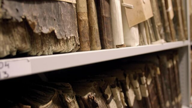 Close up of very old books stacked on metal shelves. Restoration of books in archives. Vilnius, Lithuania - 05 15 2023.