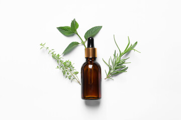 Bottle of essential oil and different herbs on white background, flat lay
