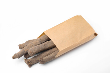 Paper bag with raw salsify roots on white background