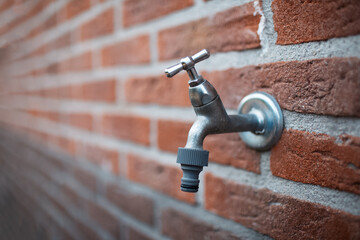 Close-up of metal outdoor tap on bricks wall.