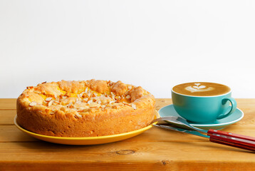 Closeup cup of coffee cappuccino and homemade pie with apples and orange on wooden table. Copyspace.