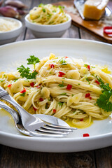 Spaghetti aglio e olio with parmesan and garlic on wooden table
