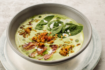 Spinach cream soup with bacon and crackers in a restaurant on the table
