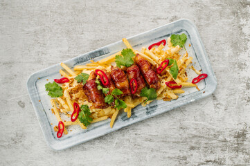 A dish of french fries with bacon and cheese sauce in a restaurant on the table