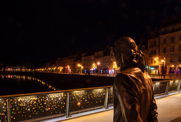 Besancon, France - August 7, 2023: Life size Jouffroy d'Abbans statue on the Pont Battant watching the Quai Vauban, the Doubs River and the Chaudanne hill in the background. Blue hour photo.