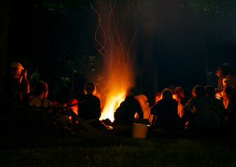 Fototapeta na wymiar People around a bonfire at night. Figure silhouettes. Unrecognizable. Warm atmosphere.