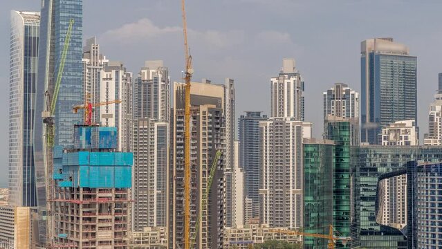 Cityscape with skyscrapers of Dubai Business Bay and water canal aerial timelapse. Construction site with many cranes. Modern skyline with residential and office towers on waterfront.