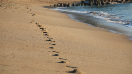 Footprints a barefoot runner on beach. Barefoot trail, step track on sand texture. Bare human feet on wet sand. Footprints on beach at dawn
