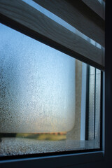  Close-up view of steamy condensate on a leaky window in a house.