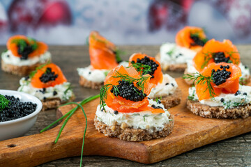 Cocktail canapes with smoked salmon, cream cheese and caviar on rye bread - gourmet party food.
