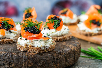 Cocktail canapes with smoked salmon, cream cheese and caviar on rye bread - gourmet party food. - obrazy, fototapety, plakaty