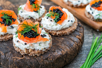 Cocktail canapes with smoked salmon, cream cheese and caviar on rye bread - gourmet party food.