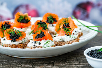 Cocktail canapes with smoked salmon, cream cheese and caviar on rye bread - gourmet party food.