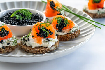 Cocktail canapes with smoked salmon, cream cheese and caviar on rye bread - gourmet party food.