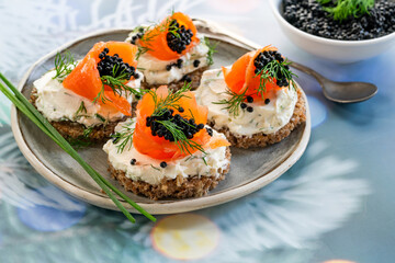 Cocktail canapes with smoked salmon, cream cheese and caviar on rye bread - gourmet party food.