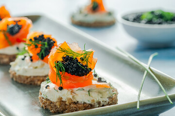 Cocktail canapes with smoked salmon, cream cheese and caviar on rye bread - gourmet party food.