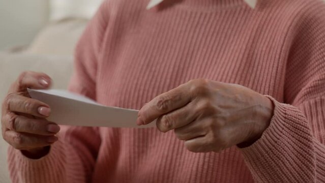 Moving shot old Caucasian retired senior woman granny female open paper envelop checking correspondence smiling happy reading letter from family feel discomfort eyesight touch glasses smile read news