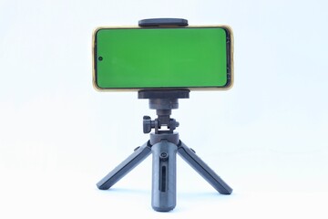 Smartphone stand on holder isolated on white background. green screen on smartphone