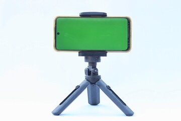 Smartphone stand on holder isolated on white background. green screen on smartphone