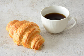 cup of coffee with croissant on gray background copy space   