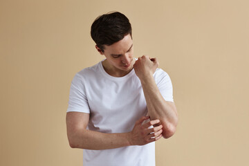 Minimal portrait of young man scratching skin while suffering from psoriasis, copy space