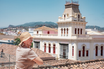 Happy traveler senior woman visiting La Laguna in Santa Cruz de Tenerife admiring cityscape from...