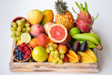Close up view of wooden basket full of mixed ripe colorful fruit. Tropical, seasonal, healthy eating concept