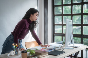 Graphic designer freelance women reading data to thinking creative ideas for logo brand while typing on computer and working to designing about graphic design with technology equipment in home studio