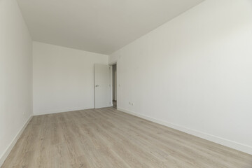 Large empty room with plain white painted walls, white wooden skirting boards and white oak wooden floors